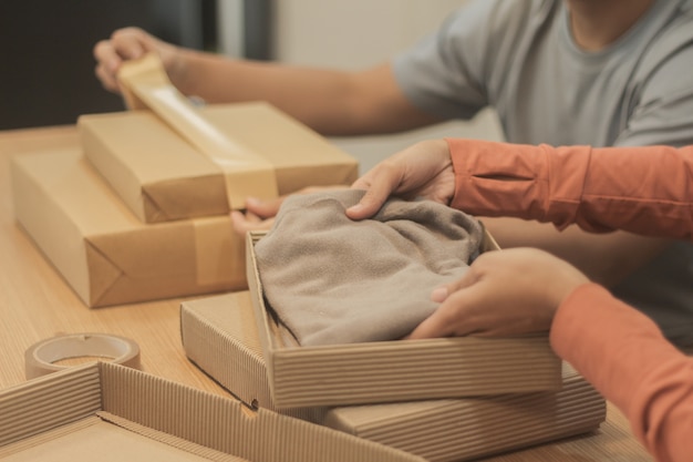 Free photo people putting clothes inside boxes and wrapping them