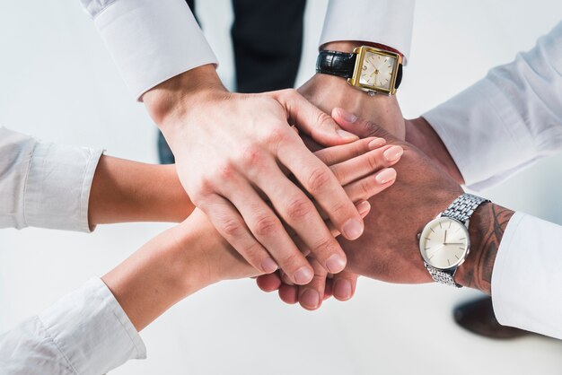 People putting stacked hands together promising help and support against white backdrop