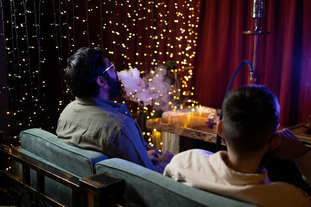 People relaxing by vaping from a hookah in a bar