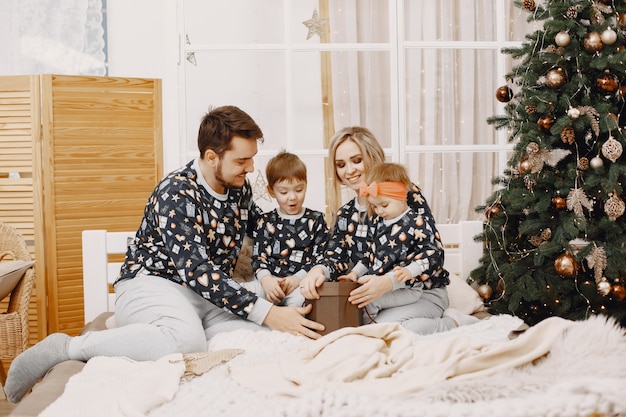 People repairing for Christmas. People sitting on a bed. Family is resting in a festive room.