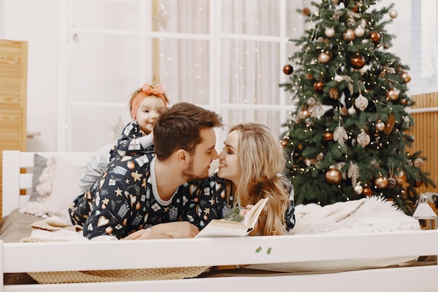 People repairing for Christmas. People sitting on a bed. Family is resting in a festive room.