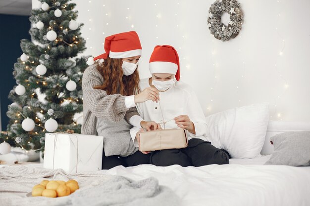 크리스마스를 돌보는 사람들. 코로나 바이러스 테마. 어머니는 그녀의 아들과 함께 연주. 흰색 스웨터에 소년입니다.