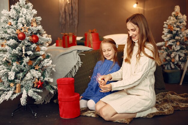 People reparing for Christmas. Kid with bengal lights. Family is resting in a festive room. Child in a blue sweater.