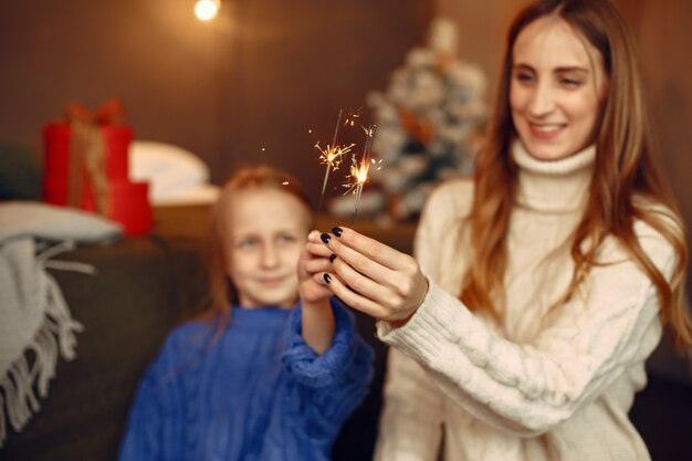 크리스마스를 돌보는 사람들. 벵골 빛을 가진 아이. 가족은 축제 방에서 쉬고 있습니다. 파란색 스웨터에 아이입니다.