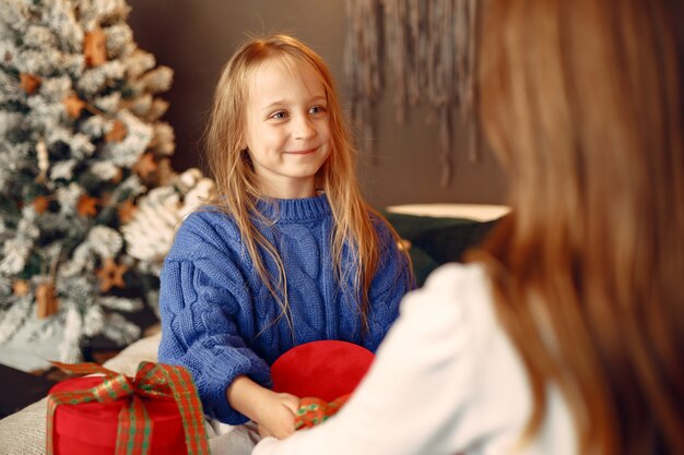 People reparing for Christmas. Mother playing with her daughter. Family is resting in a festive room. Child in a blue sweater.