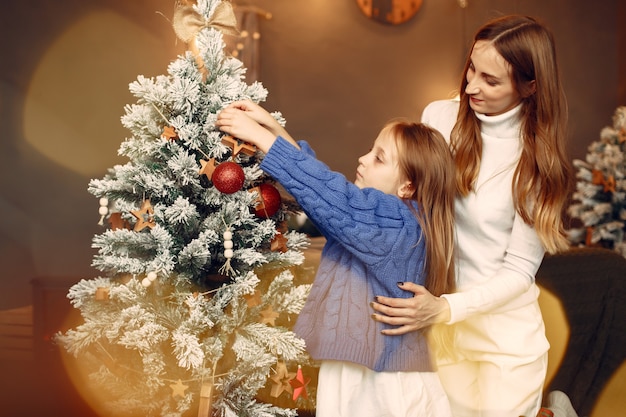 クリスマスの準備をしている人。娘と遊ぶ母。家族はお祭りの部屋で休んでいます。青いセーターを着た子供。