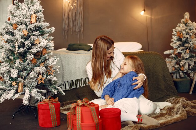クリスマスの準備をしている人。娘と遊ぶ母。家族はお祭りの部屋で休んでいます。青いセーターを着た子供。