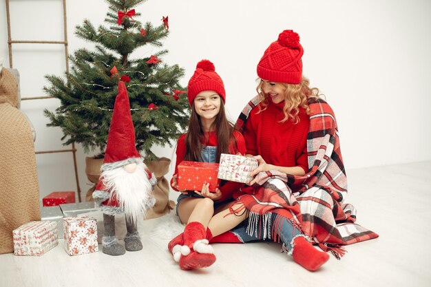 クリスマスの準備をしている人。娘と遊ぶ母。家族はお祭りの部屋で休んでいます。赤いセーターを着た子供。