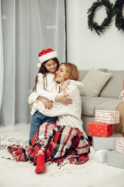 People reparing for Christmas. Mother playing with her daughter. Family is resting in a festive room. Child in a red sweater.