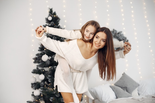 Free photo people reparing for christmas. mother playing with her daughter. family is resting in a festive room. little girl in a white dress.