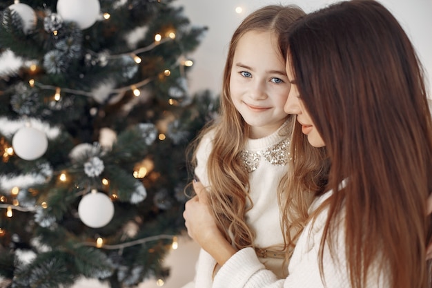 Free photo people reparing for christmas. mother playing with her daughter. family sitting on a bed. little girl in a white dress.