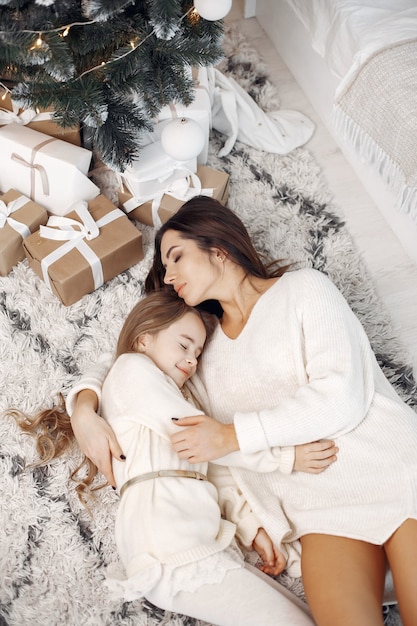 크리스마스를 준비하는 사람들. 그녀의 딸과 함께 노는 어머니. 크리스마스 트리 옆에 앉아 있는 가족. 하얀 드레스를 입은 어린 소녀.