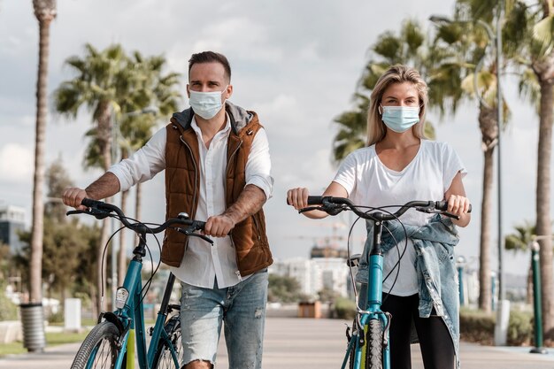 People riding a bike while wearing a medical mask