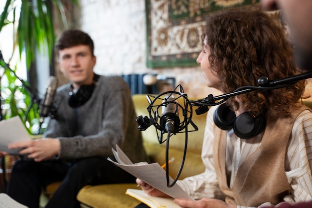 Foto gratuita persone che gestiscono un podcast con microfoni e cuffie dallo studio