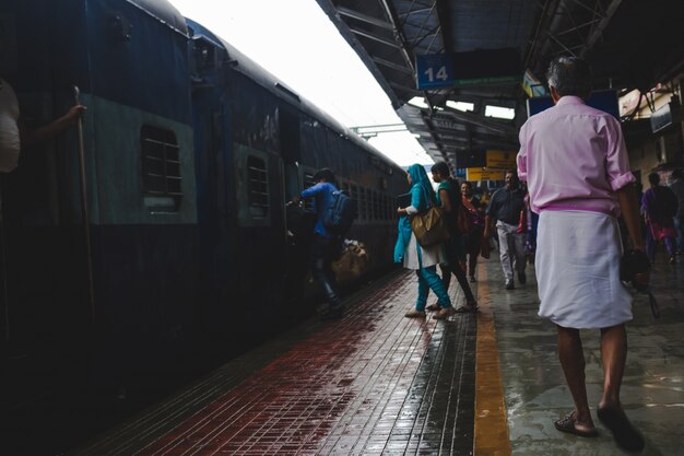 People rushing to board a train as a man in a pink shirt walks by