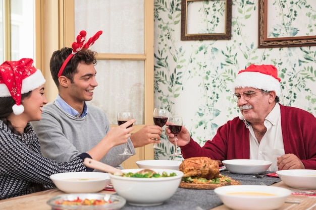 People in Santa hats clanging glasses at Christmas table