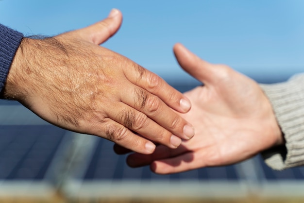 Люди пожимают друг другу руки возле завода по производству альтернативной энергии