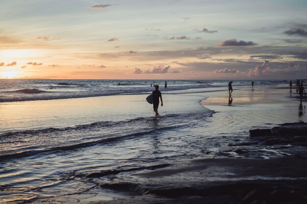 people on the shore of the ocean at sunset. 