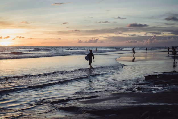 people on the shore of the ocean at sunset. 