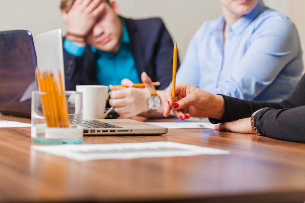 People siting at desk holding pencils