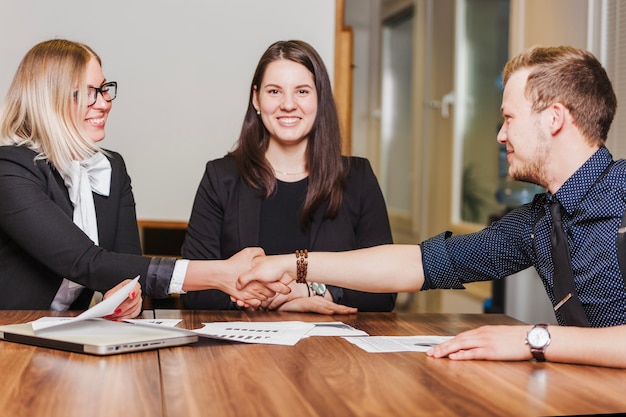 People sitting at desk smiling shaking hands