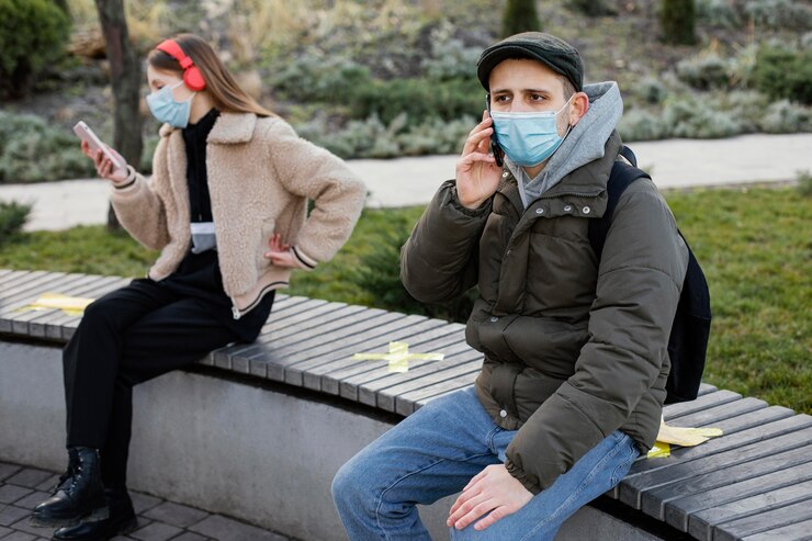 Free Photo people sitting at distance and wearing mask