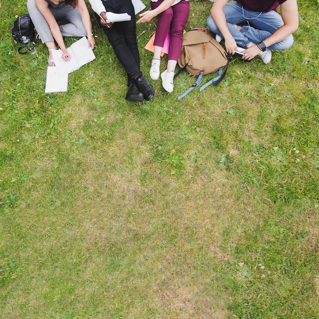 Free photo people sitting on grass studying