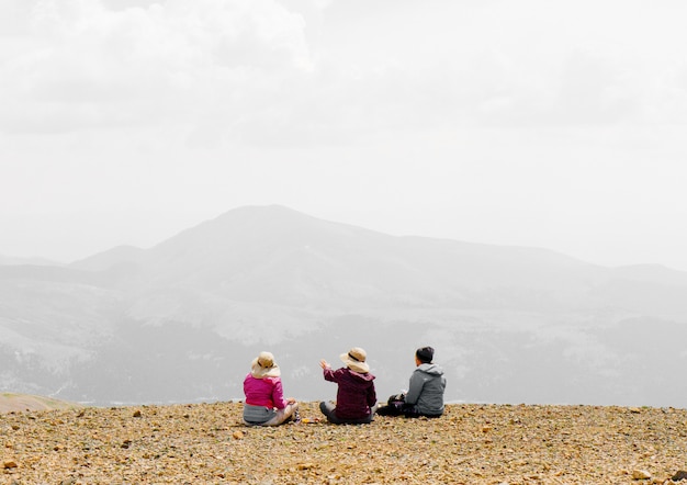 무료 사진 사람들은 산의 가장자리에 앉아 경치를 즐기고 안개 배경으로 이야기