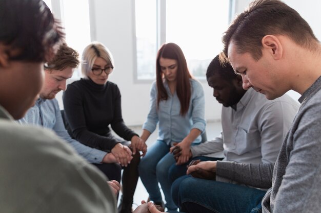 People standing in a circle with closed eyes and holding hands