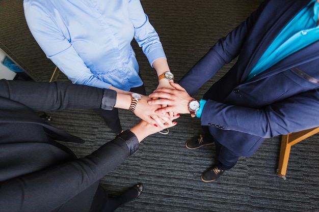 Persone in piedi in ufficio che tengono le mani insieme