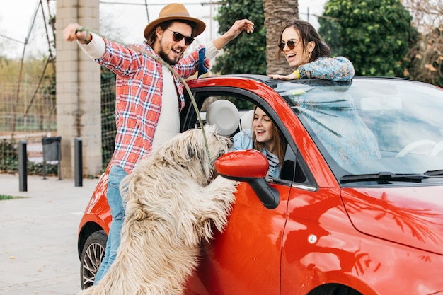 People standing with big dog near car 