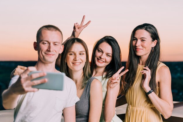 People taking selfie on rooftop at dawn