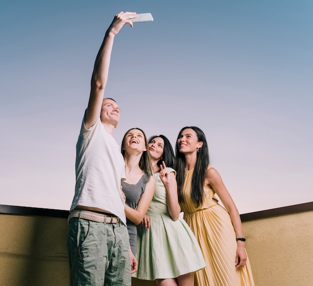 People taking selfie on rooftop from below