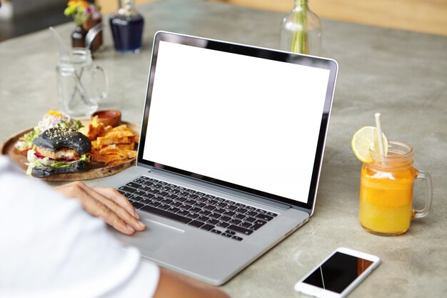 People, technology, communication and leisure concept. Cropped rear view of young man in white t-shirt surfing internet, checking newsfeed via social media