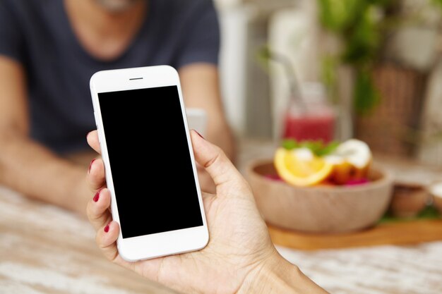 People, technology and lifestyle concept. Close up shot of female hand holding smart phone