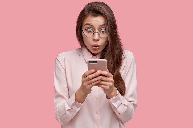 people, technology, reaction concept. stunned dark haired woman stares with eyes popped out, stands nervous and confused