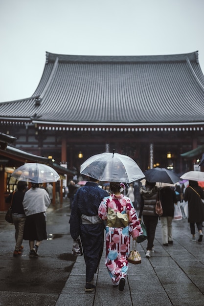 Persone che camminano per strada tenendo gli ombrelli che vanno alla pagoda