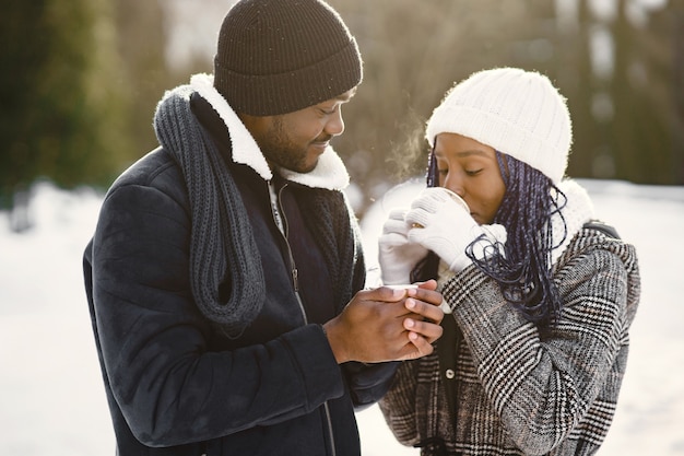 La gente cammina fuori. giornata invernale. coppia africana con caffè.