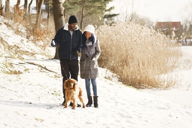 人々は外を歩きます。冬の日。犬とアフリカのカップル。