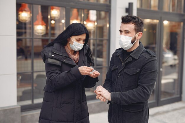 알코올 젤을 사용하는 동안 거리에 보호 마스크를 착용하는 사람들