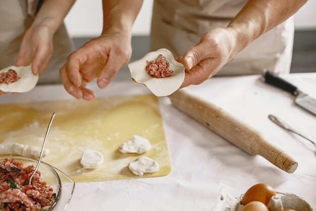 People while preparing dumplings. Asian people in aprons.