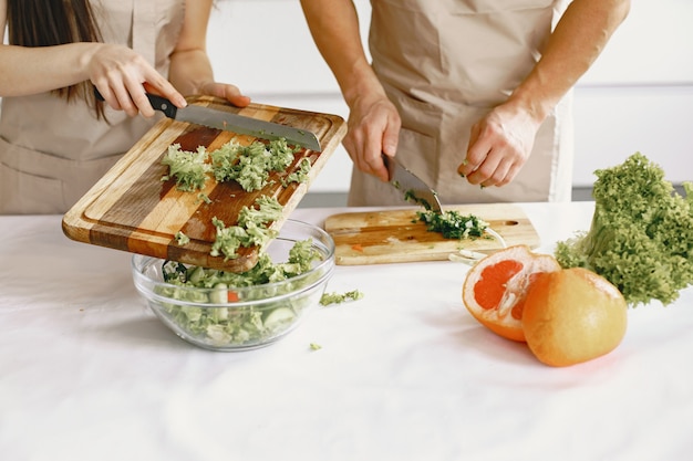 People while preparing fresh vegetables food salad. Asian people in aprons.