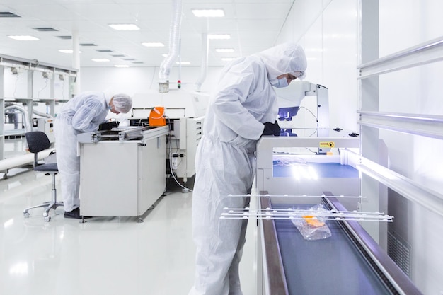 La gente in costumi d'isolamento bianchi che lavorano in laboratorio