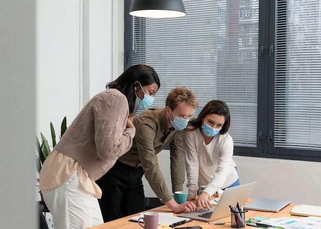 Foto gratuita persone con maschere facciali che lavorano insieme per un progetto