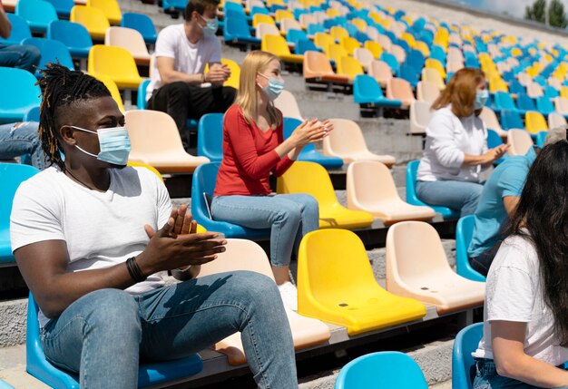 People with medical masks looking at a game