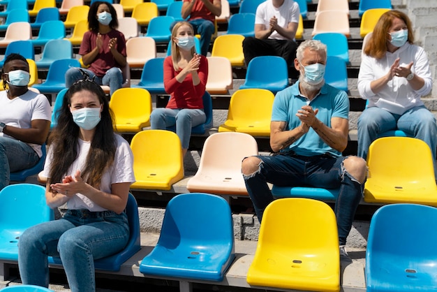 People with medical masks looking at a game