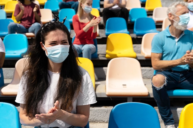 Free photo people with medical masks looking at a game