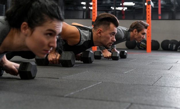 Free photo people working out indoors together with dumbbells