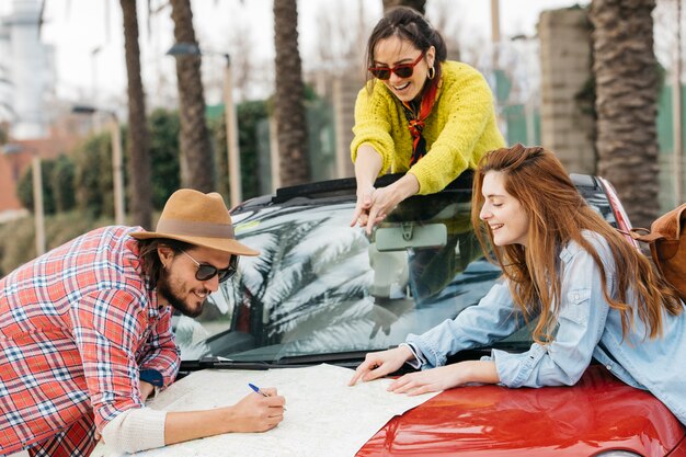 People writing on road map with pencil on car 