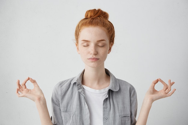 사람, 요가 및 건강한 라이프 스타일 개념. 실내 명상, 마음의 조각 연습, mudra 제스처에 손가락을 유지하면서 눈을 감고 화려한 젊은 빨간 머리 여자의 초상화